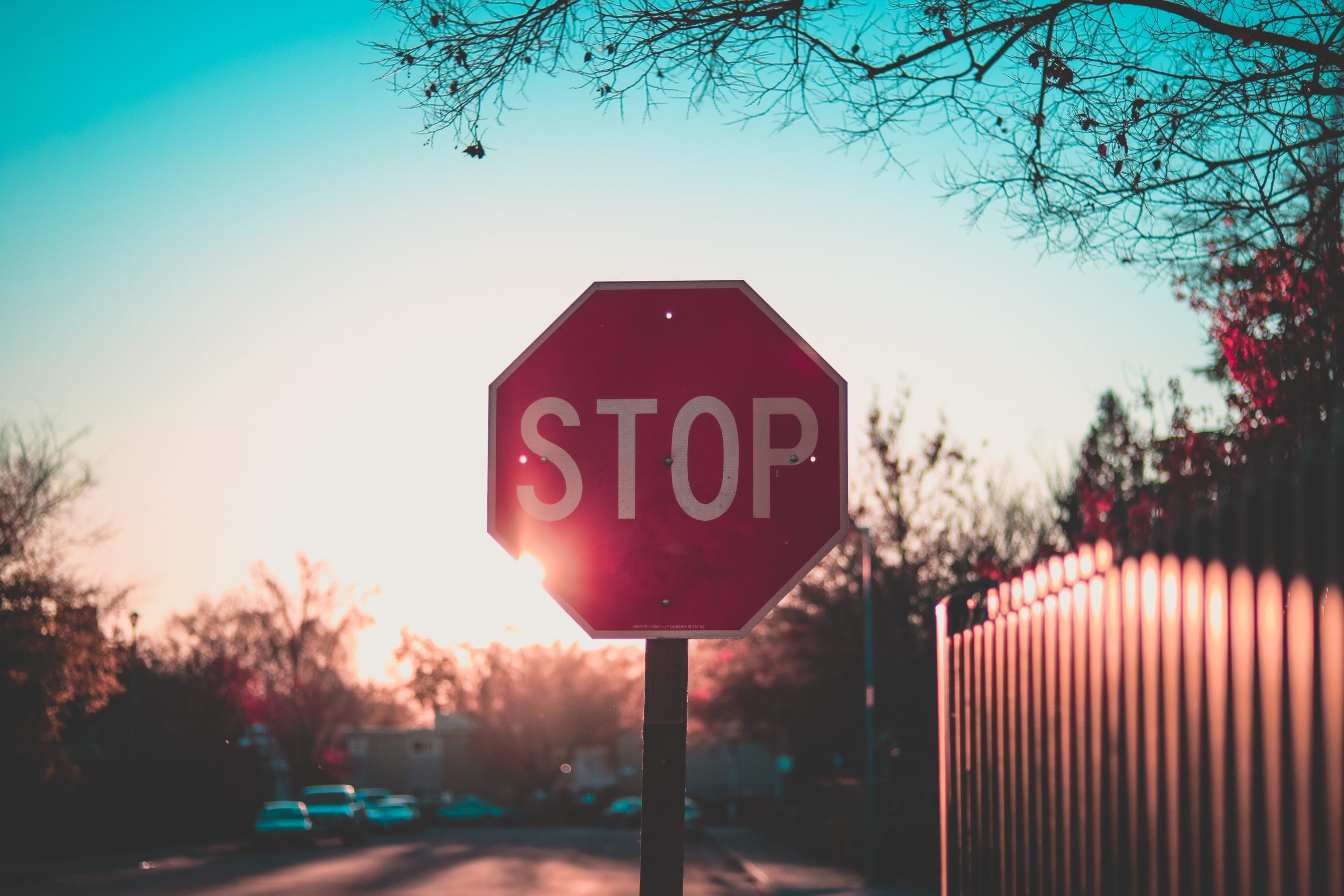 A backlit Stop Sign on a quiet residential street.