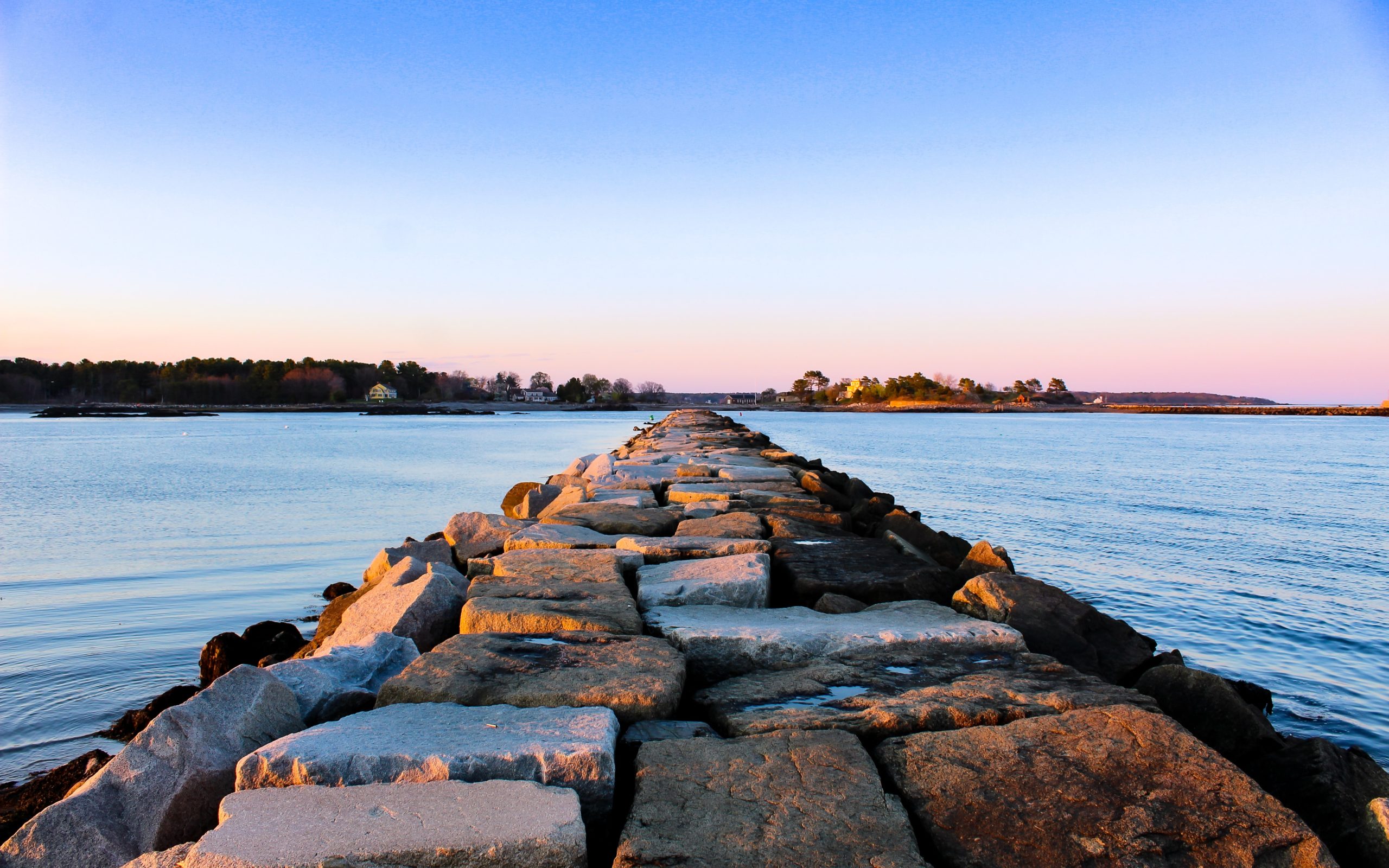 Grey rocks form a path leading out into a body of water